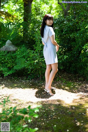 A woman standing in front of a window wearing a blue and white dress.