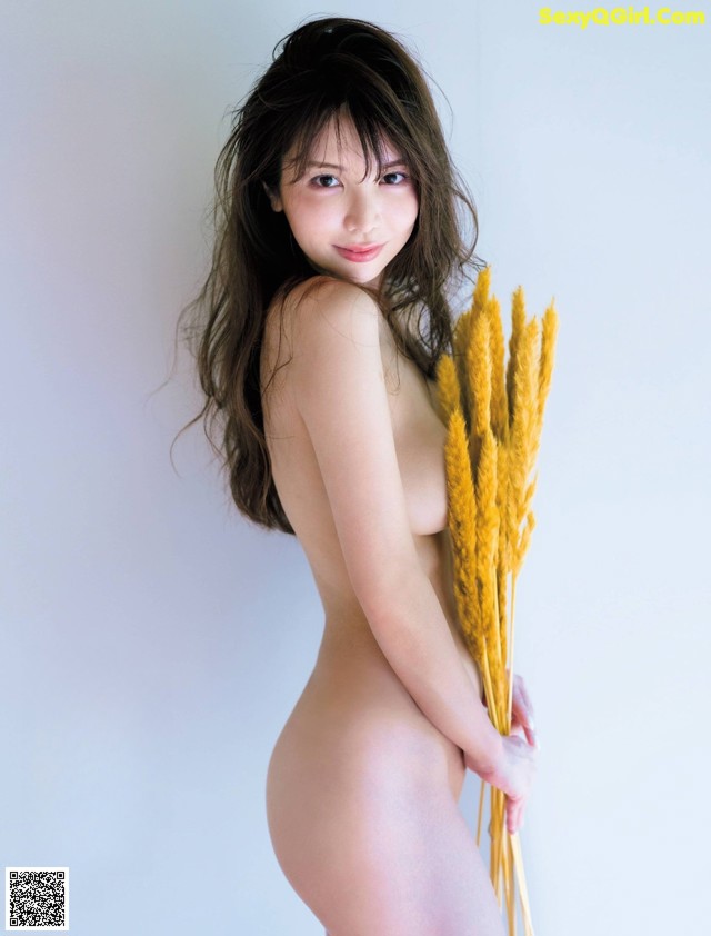 A naked woman holding a bunch of wheat.