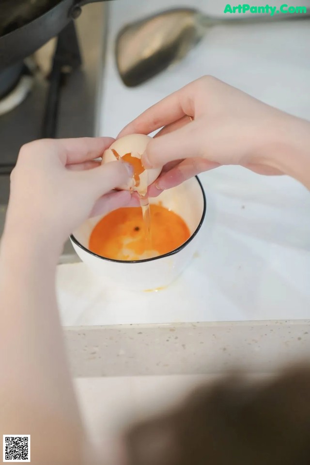 A person is peeling an egg into a bowl.