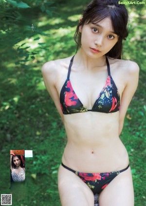 A woman in a white bikini sitting on a tatami mat.