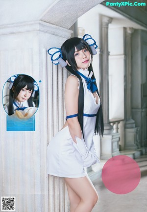 A woman in a white and blue outfit leaning against a wall.