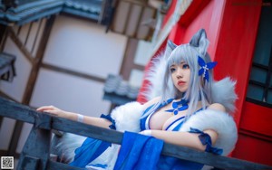 A woman in a blue dress sitting on a wooden bench.