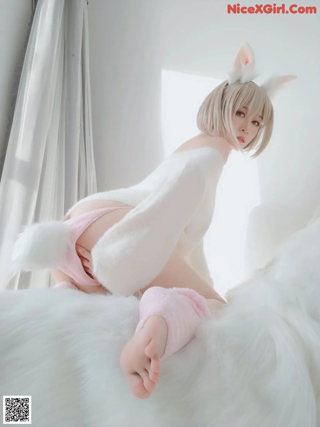 A woman in a bunny costume is sitting on a bed.