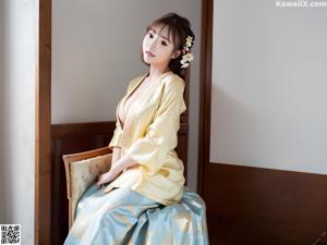 A woman in a blue robe sitting on a white table.