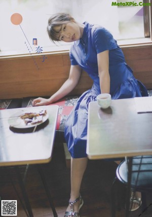 A woman in a blue dress standing on a street.