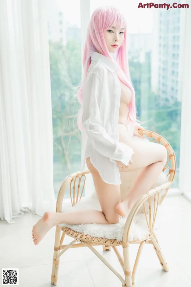 A woman with pink hair sitting on a chair.