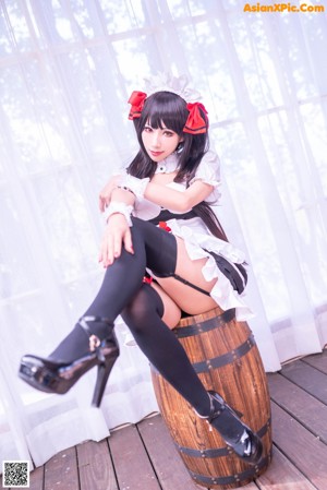 A woman in a maid outfit sitting on a chair.