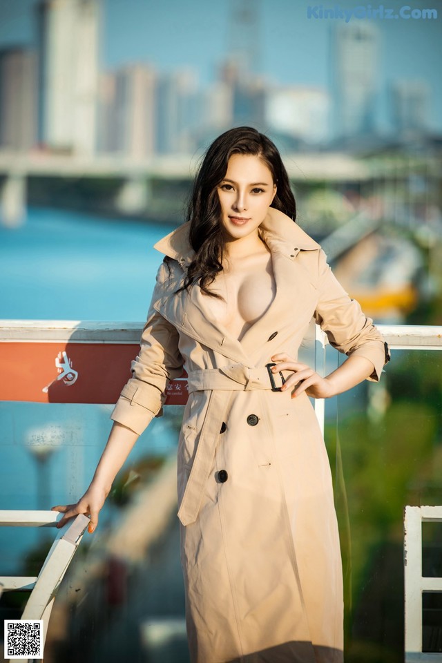 A woman in a trench coat posing for a picture.