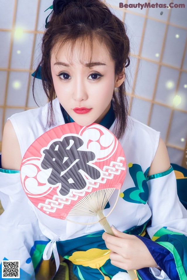 A woman in a chinese dress holding a fan.