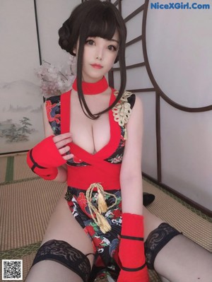 A woman in a red and black outfit is posing for the camera.