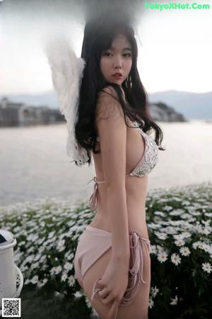 A woman in a bikini with angel wings posing for the camera.