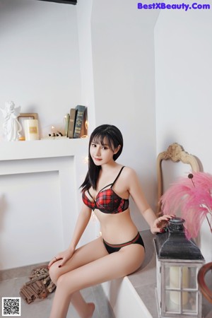 A woman in a red and black bikini posing in front of a mirror.