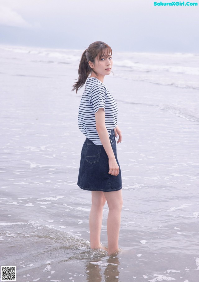 A woman standing in the water at the beach.