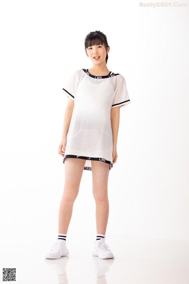 A woman in a white shirt and black shorts posing for a picture.