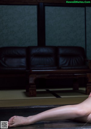A naked woman laying on a bed next to a window.