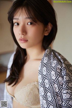 A woman in a kimono leaning against a brick wall.
