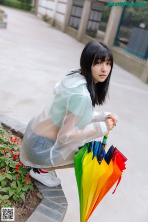 A woman in a white dress leaning against a green fence.