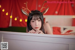 A woman in a reindeer costume laying on a bed.