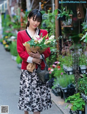 A woman sitting on a couch holding a white flower.