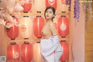 A woman in a kimono posing in front of a window.