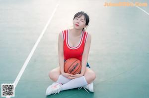 A woman in shorts and a red shirt holding a basketball.
