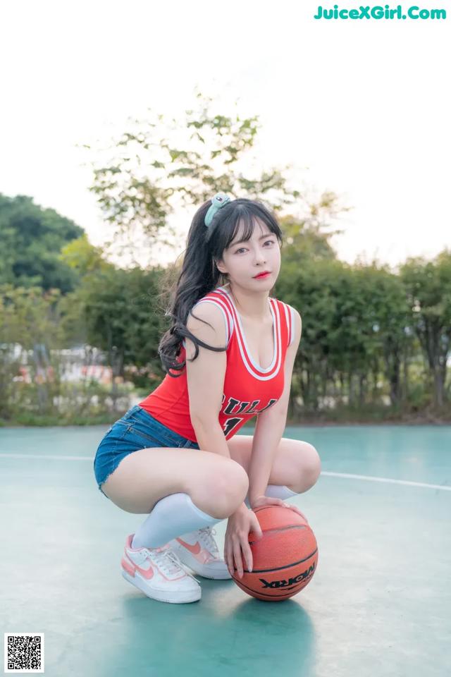 A woman kneeling down with a basketball on a basketball court.