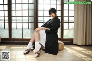 A woman sitting on the floor in front of a window.